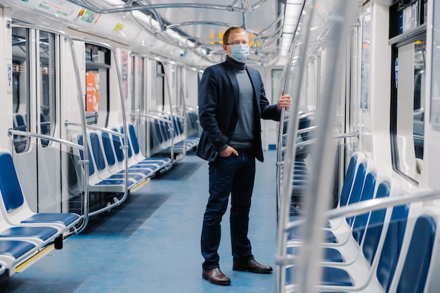 mannelijke ondernemer in pak, medisch masker, virusbescherming en quarantaine beschermt zichzelf tegen het coronavirus in het openbaar vervoer