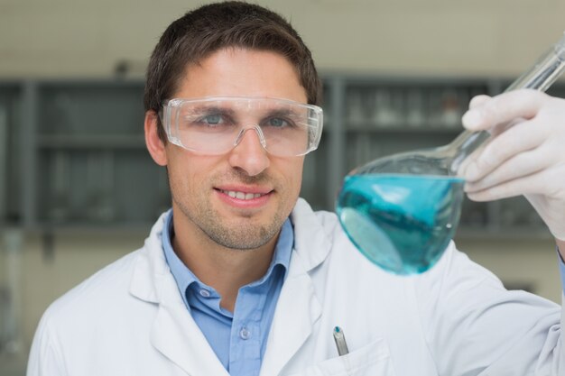 Mannelijke onderzoeker die fles met blauwe vloeistof in het laboratorium houdt