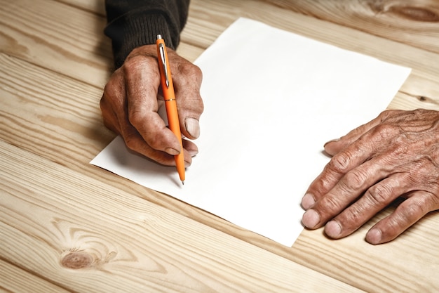 Mannelijke oude handen schrijft op een blanco vel papier