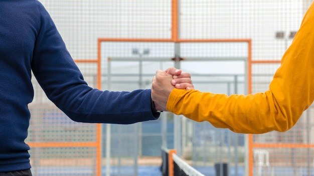 Mannelijke padelspelers handdruk na het winnen van een padelwedstrijd in een blauwe paddelbaan indoor Tennisspelers schudden elkaar de hand op een buitenbaan