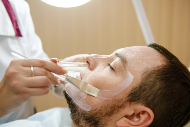 Mannelijke patiënt krijgt gezichtsbehandeling in schoonheidskliniek