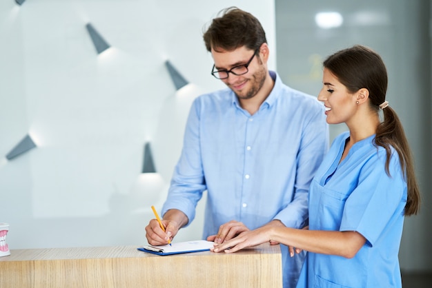 Mannelijke patiënt ondertekening van documenten in tandheelkundige kliniek