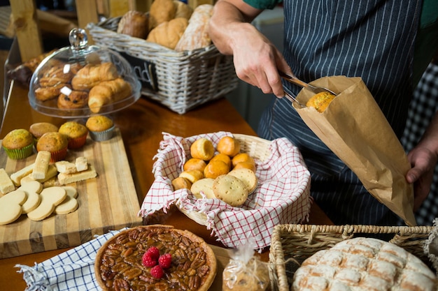 Mannelijke personeel koekjes in een papieren zak verpakken