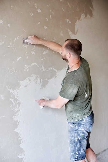 Foto mannelijke pleistermuur met plamuurmes close-up muuroppervlak bevestigen en voorbereiding voor schilderen