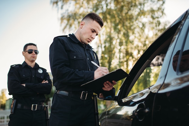 Mannelijke politieagenten controleren voertuig op de weg