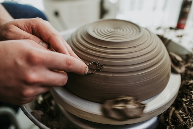 Mannelijke pottenbakker die aardewerk van klei maakt op een spinwiel