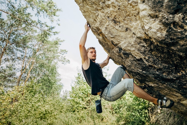 Foto mannelijke rotsklimmer die op de klip hangt