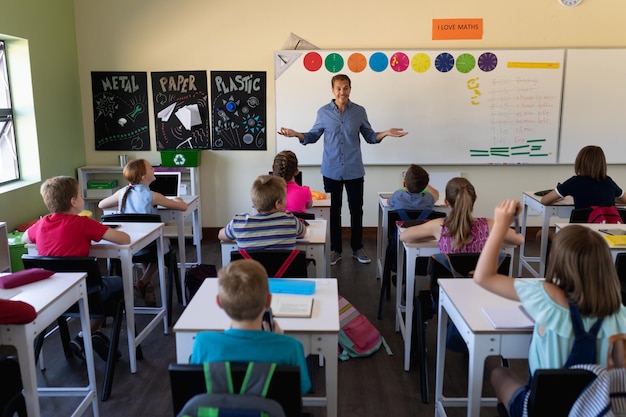 Mannelijke schoolleraar die zich in een klaslokaal van de basisschool bevindt