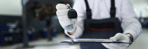 Foto mannelijke servicemedewerker geeft sleutels van vaste auto aan eigenaar en onderhoudsdocumentatie