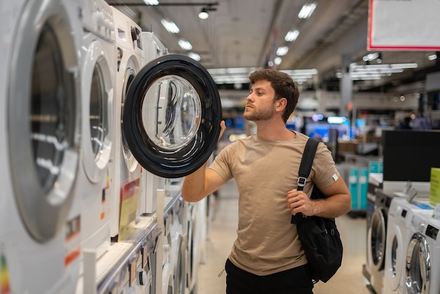 Mannelijke shopper die in de wasmachine kijkt