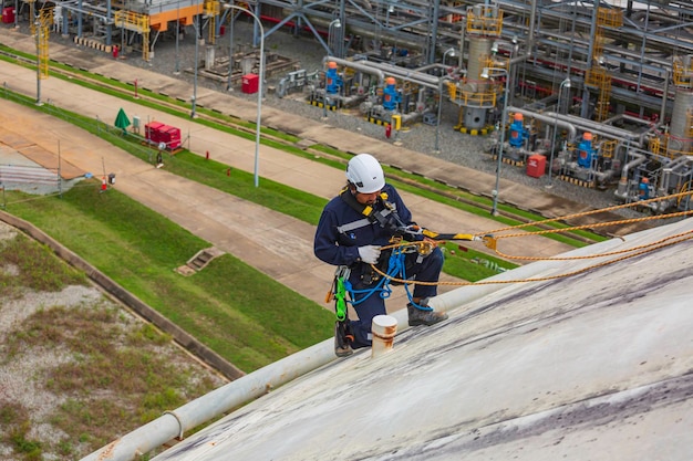 Mannelijke sitdown werknemer inspectie dragen van veiligheid eerste harnas touw veiligheidslijn werken op een hoogte