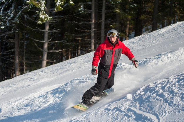 Mannelijke snowboarder glijdt van de berg naar beneden