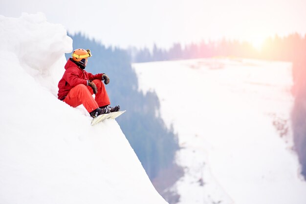 Mannelijke snowboarder op de top van de besneeuwde heuvel