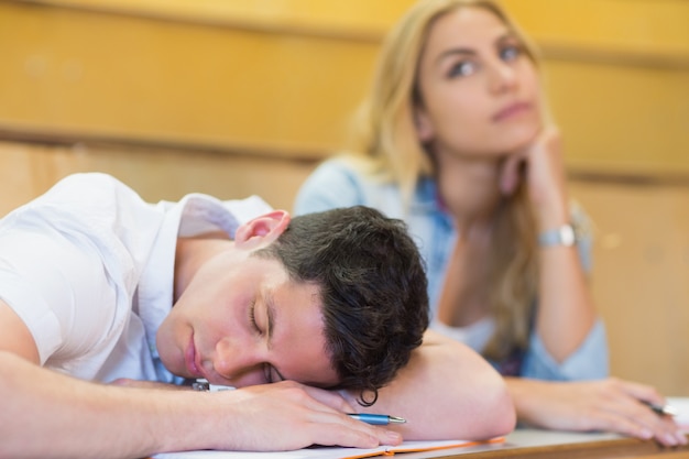 Mannelijke student die tijdens klasse bij de universiteit in slaap valt