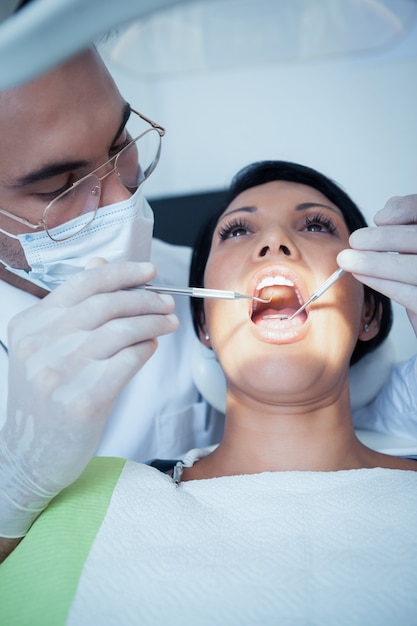 Mannelijke tandarts die de tanden van de vrouw onderzoeken
