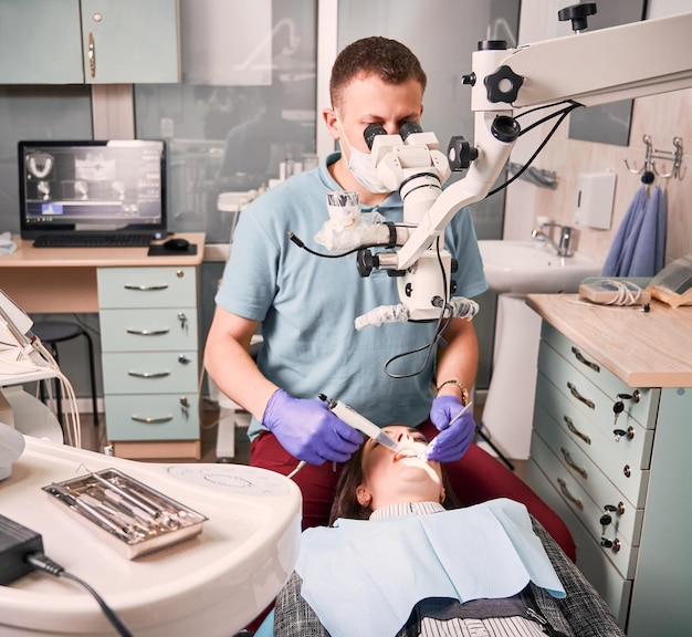 Mannelijke tandarts die geduldige tanden in moderne kliniek behandelt