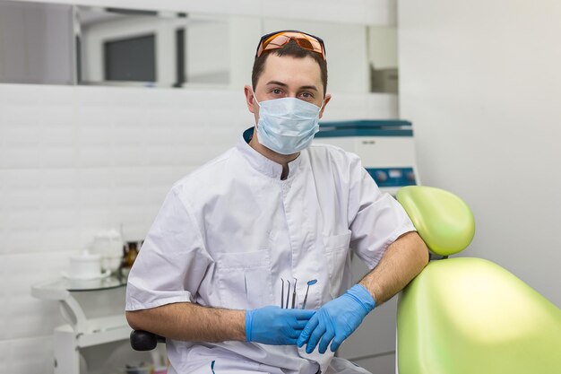 Mannelijke tandarts die zich over medische kantoorachtergrond bevindt Gezondheidszorgberoep stomatologie en geneeskundeconcept