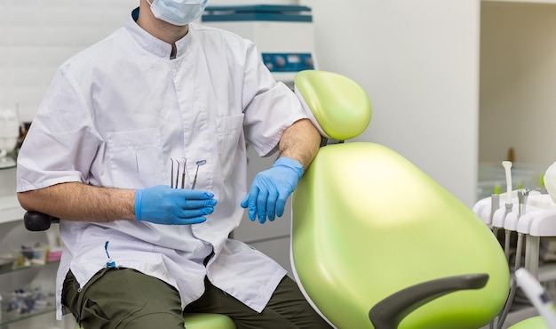 Mannelijke tandarts met hulpmiddelen over medische kantoorachtergrond Gezondheidszorgberoep stomatologie en geneeskundeconcept