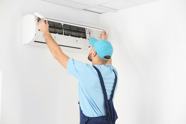 Mannelijke technicus die airconditioner binnenshuis repareert