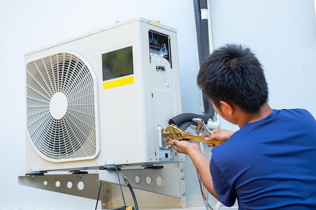 Foto mannelijke technicus die buiten een airconditioner installeert om het huishouden te koelen in de zomer luchtcompressor elektronische hete zomer hoge temperatuur tropische landen