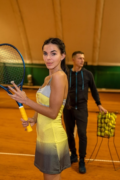 Mannelijke tenniscoach laat een vrouwelijke cliënt zien hoe ze op de baan moet dienen