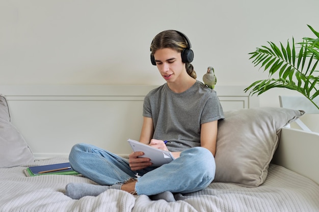 Mannelijke tiener met groene papegaai op zijn schouder met schoolboeken