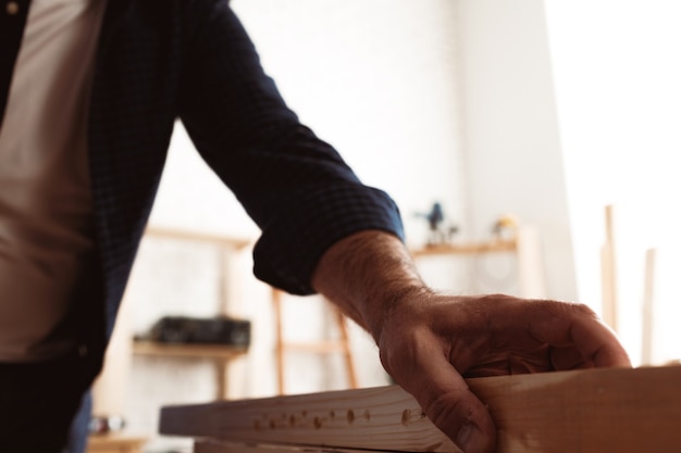 Mannelijke timmerman aan het werk met een houten balk in een werkplaats