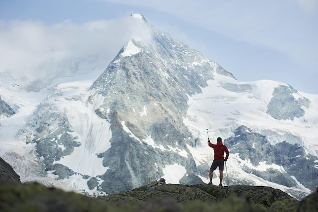 Mannelijke toerist die besneeuwde rotswanden van de prachtige penning-alpen in zwitserland beklimt