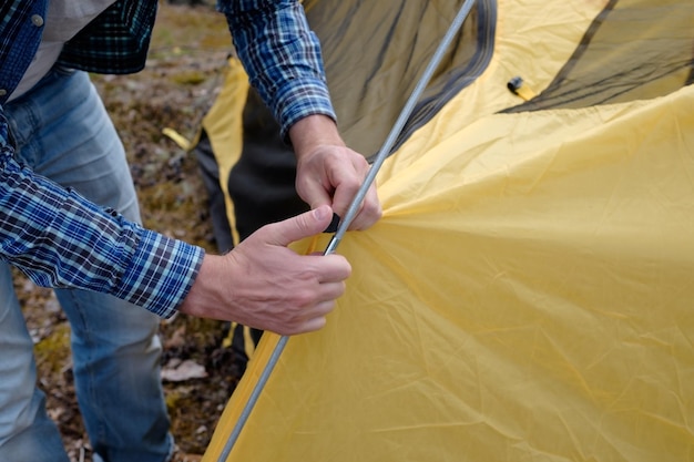 Mannelijke toerist die een tent maakt bij boskamp