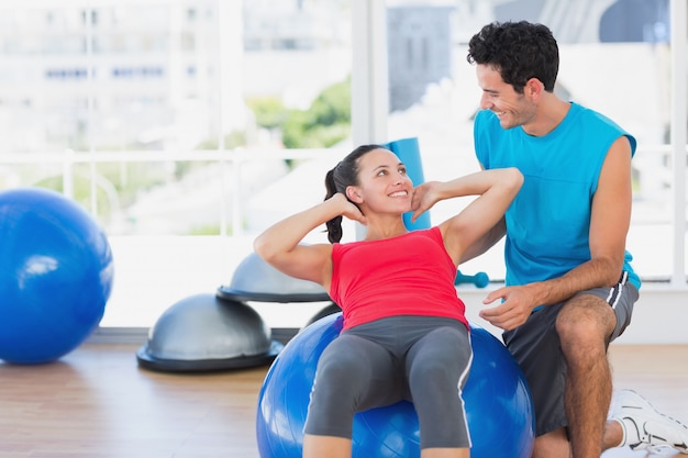 Mannelijke trainer die vrouw met haar oefeningen helpen bij gymnastiek