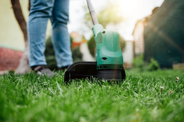 Mannelijke tuinman die het gras snijdt