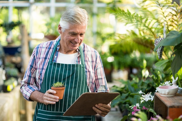 Mannelijke tuinman die ingemaakte installatie en klembord houdt