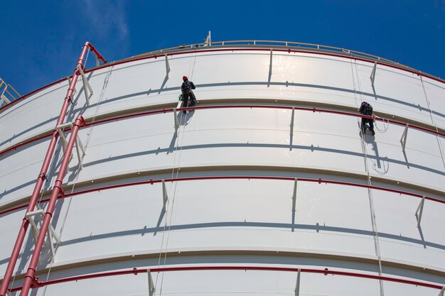 Mannelijke twee werknemer down hoogte tank shell plaat touw ladder toegang veiligheidsinspectie van dikte opslagtank gas propaan.