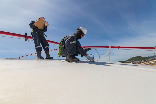 Mannelijke twee werknemers zijn voor inspectie van ultrasone dikte dakplaat koepel top van opslagtank.