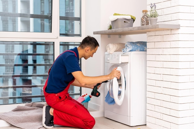 mannelijke volwassen reparateur met gereedschap en klembord wasmachine in badkamer controleren