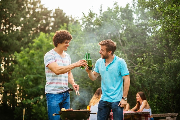 Mannelijke vrienden die barbecue maken en bier drinken