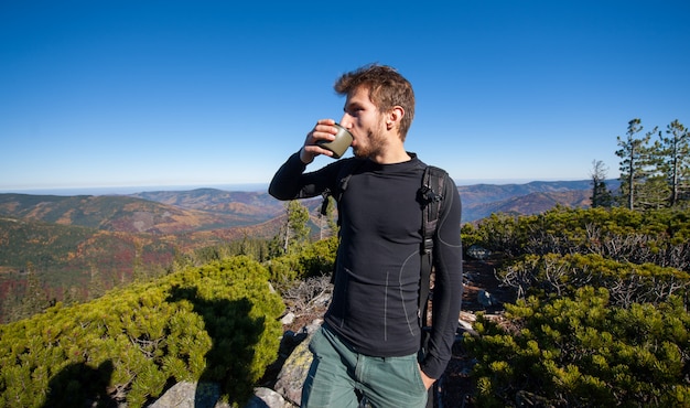 Mannelijke wandelaar het drinken van thee op de top van de berg