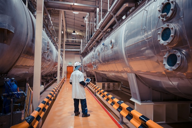Mannelijke werkinspectieproces melkpoederkelder bij de fabriek met horizontale roestvrijstalen tanks