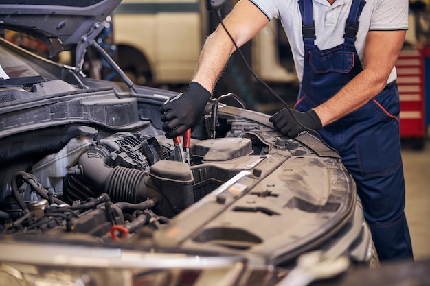 Mannelijke werknemer die auto repareert bij reparatieservicestation