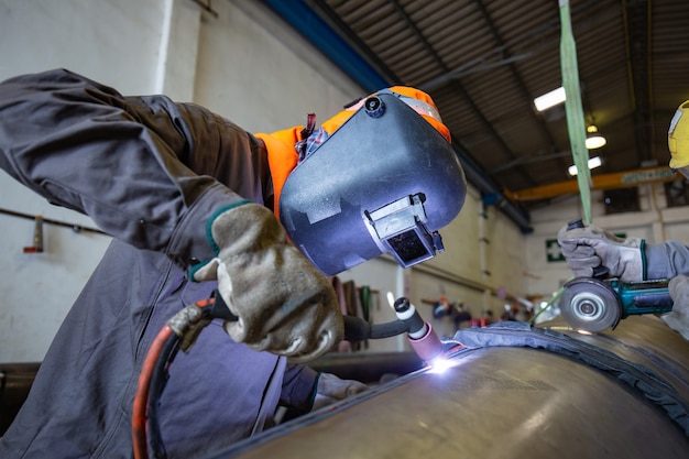 Mannelijke werknemer die beschermende kleding draagt van reparatiepijp roestvrij argon lassen industriële constructie