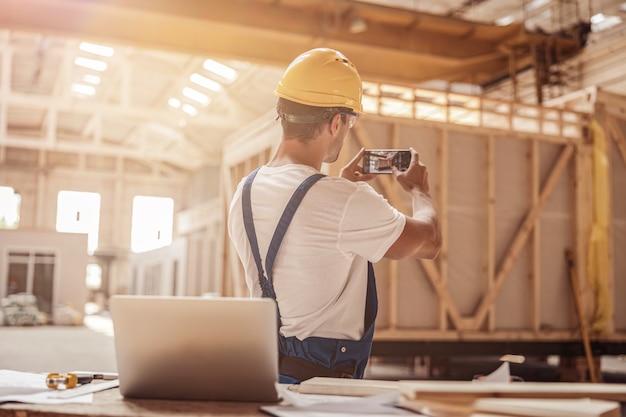 Mannelijke werknemer die bouwfoto maakt met mobiele telefoon