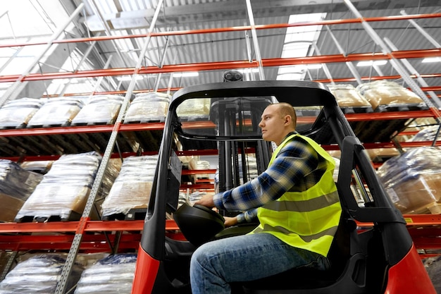 Foto mannelijke werknemer die een heftruck in een magazijn rijdt