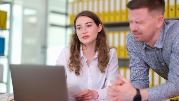 Mannelijke werknemer en vrouwelijke manager bestuderen een rapport op laptop