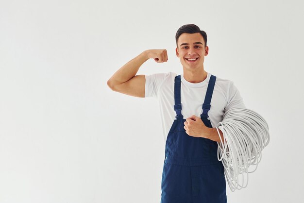 Mannelijke werknemer in blauw uniform staande binnenkant van studio tegen witte achtergrond