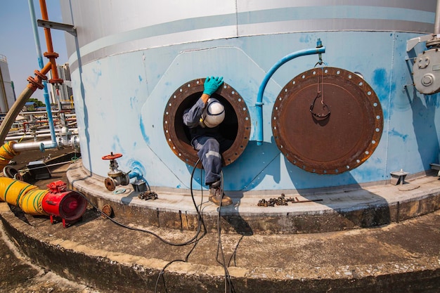 Mannelijke werknemer in de tank koolstof chemische olie interface gebied besloten ruimte veiligheid.