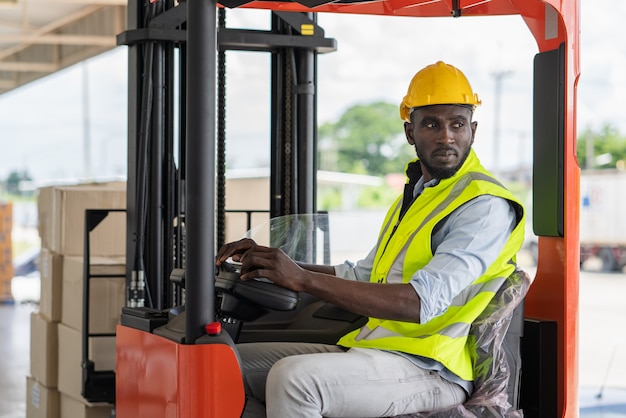 Mannelijke werknemer in veiligheidsvest en helm een heftruck besturen