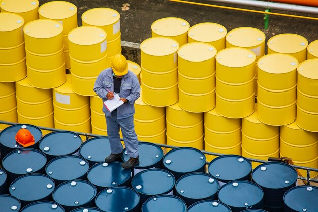 Foto mannelijke werknemer inspectie record drum olie voorraad vaten geel verticaal of chemisch voor transport vrachtwagen man in de industrie.