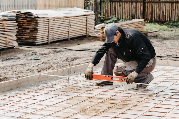 mannelijke werknemer meet het constructieniveau van wapening voor de fundering van een huis in aanbouw