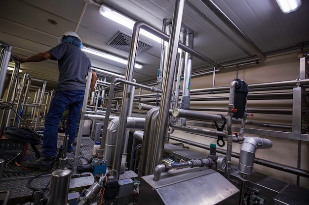 Mannelijke werknemer moderne melkkelder met pijpleiding roestvrij staal