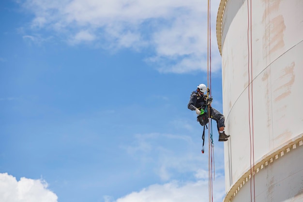 Mannelijke werknemer naar beneden hoogte tank dak touw toegang veiligheidsinspectie dikte las van opslagtank gas